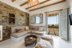 a living room with a stone wall and a couch at Parian Philoxenia Villa, Santa Maria Beach in Kampos Paros