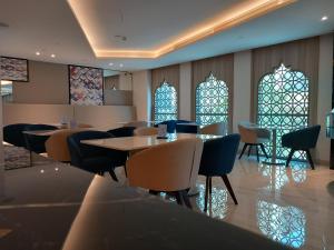 restauracja ze stołami i krzesłami oraz witrażami w obiekcie C - Hotel and Suites Doha w mieście Doha