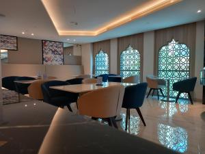 C - Hotel and Suites Doha في الدوحة: مطعم بطاولات وكراسي ونوافذ زجاجية ملطخة