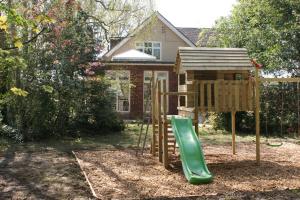 a playground with a green slide in front of a house at Spacious 4 bed family cottage in parkland setting in York