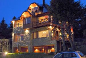 una casa grande con un coche aparcado delante de ella en El Nautico Lodge Bariloche en San Carlos de Bariloche