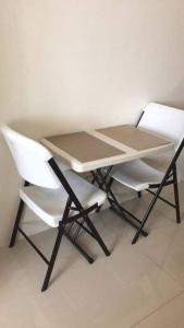 a table and two white chairs sitting next to a white wall at Eagle's Nest - Furnished 1BR Condo w/ WIFI in Manila