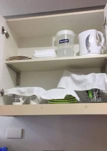 a shelf with dishes and cups and towels on it at Eagle's Nest - Furnished 1BR Condo w/ WIFI in Manila