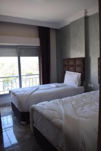 een hotelkamer met 2 bedden en een balkon bij Baron Palace hotel suites in Aqaba