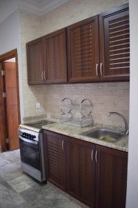 una cocina con armarios de madera y fregadero en Baron Palace hotel suites, en Áqaba