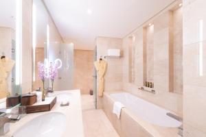 een witte badkamer met een bad en een wastafel bij Shaza Doha in Doha