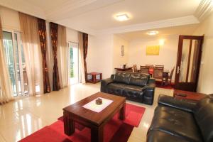 sala de estar con mesa y muebles de cuero negro en Residence MASSOU en Yaundé