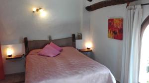 a bedroom with a bed with a pink pillow at L'Almàssera Casa Rural & Restaurant in Margarida