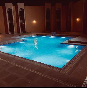 a large pool with blue water in a building at Basrah International Airport Hotel in Al Başrah