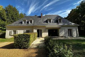 uma velha casa branca com um telhado cinzento em Spacious house in a wooded park enclosed by walls and its swimming pool em Saint-Cyr-sur-Loire