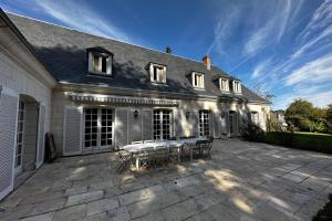 a patio in front of a house with a table at Spacious house in a wooded park enclosed by walls and its swimming pool in Saint-Cyr-sur-Loire