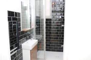 a black tiled bathroom with a sink and a mirror at Grand Appartement Confort in Vichy +28 photos