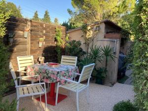 una mesa y sillas en un patio trasero con una valla en Studio en Provence avec piscine, en Graveson