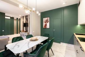ein Esszimmer mit grünen Wänden sowie einem weißen Tisch und Stühlen in der Unterkunft LEOGRAND VIP Apartments on Lesi Ukrainky 7 in Lwiw