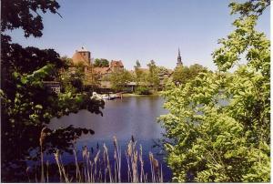 Blick auf einen See mit einer Stadt im Hintergrund in der Unterkunft Hotel am Holzhafen in Stade