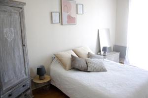 Un dormitorio con una cama blanca con almohadas. en Perigueux T2 proche du quartier historique en Périgueux