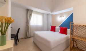 a hotel room with a white bed and red pillows at Paamonim Central Studios in Jerusalem