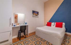 1 dormitorio con cama con almohadas rojas y escritorio en Paamonim Central Studios, en Jerusalén