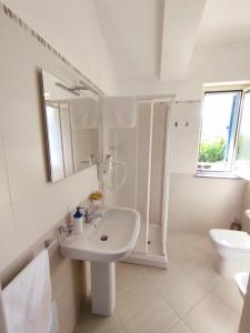 a white bathroom with a sink and a mirror at Icaro Residence Apartments with a beautiful pool in SantʼAgata di Militello