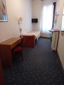 Cette chambre comprend deux lits, un bureau et une table. dans l'établissement Hotel Caneva, à Venise