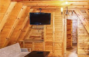 a living room with a tv in a log cabin at Amazing Home In Lukecin With 2 Bedrooms in Łukęcin