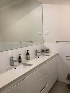 Baño blanco con 2 lavabos y espejo en Reservoir Paradise, en Melbourne