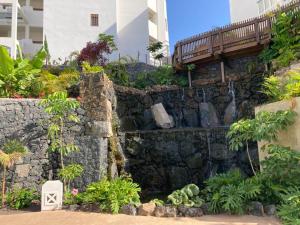 a stone wall with a waterfall in a garden at Palmmar Jardines NEW 2bedroom ISORA 0,4 Appt 105m2 with garden in Palm-mar