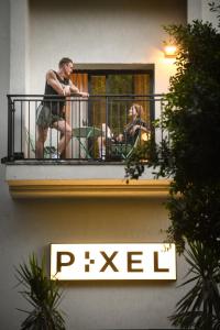 Pixel Dizengoff Square - Smart Hotel by Loginn Tel Aviv في تل أبيب: جلوس شخصين على شرفة مبنى