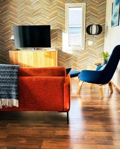 salon z pomarańczową kanapą i telewizorem w obiekcie Aurora Apartment Kilpisjärvi w mieście Kilpisjärvi