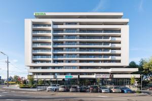 un gran edificio blanco con coches estacionados frente a él en Prima by the River, en Oradea