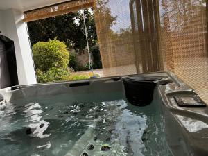 a bathtub filled with water with a trash can in it at Maison cosy avec jacuzzi privatif proche Reims in Braine