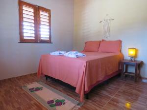 1 dormitorio con cama con sábanas rosas y ventana en Alameda dos Coqueirais en Icaraí