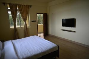 a bedroom with a bed and a flat screen tv at TreeTops Residency in Shillong