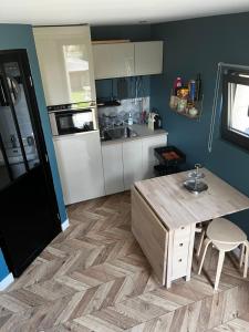 uma cozinha com uma mesa de madeira e um frigorífico em La petite Brainoise - Gîte avec salle jacuzzi 120 jets em Braine