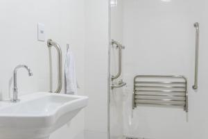 a white bathroom with a sink and a shower at HOTEL CONSAGRADO in Aparecida