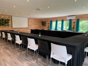 a long black table with white chairs and a screen at Domaine de Roullet in Roullet