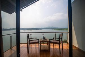 a table and chairs on a balcony with a view of the water at Shvas Island Resort in Igatpuri