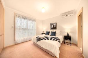 a white bedroom with a bed and a window at Charming 3BR Family Home In A Perfect Location in Narre Warren