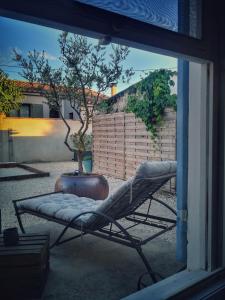 einen Stuhl, der in einem Garten mit einem Fenster sitzt in der Unterkunft Gîte paisible aux pieds des Alpilles, parking privé in Saint-Rémy-de-Provence