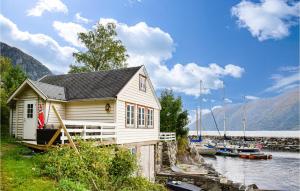 a small house next to a body of water with boats at Gorgeous Home In Vallavik With House Sea View in Kaland