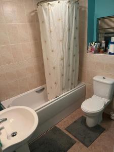 a bathroom with a toilet and a sink and a shower curtain at Sunny House in Haydock