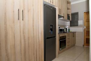 プレトリアにあるBeautiful Studio Cottage at Menlyn Maineの木製のキャビネット付きのキッチン(黒い冷蔵庫付)