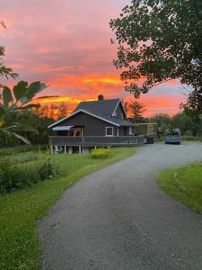 a house on a road with a sunset in the background at Unik liten leilighet i Stamsund, midt i Lofoten in Rishaugen