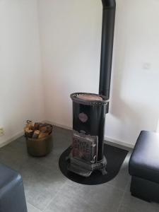 a black stove in a room with a basket of wood at L'endroit oublié - Gîtes pour 7 personnes à Spa-Francorchamps in Spa