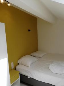 two beds in a room with yellow walls at L'endroit oublié - Gîtes pour 7 personnes à Spa-Francorchamps in Spa