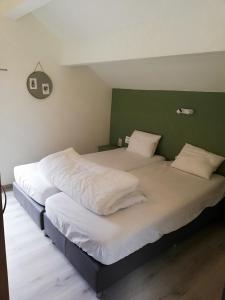 una camera da letto con due letti con lenzuola bianche e una parete verde di L'endroit oublié a Spa
