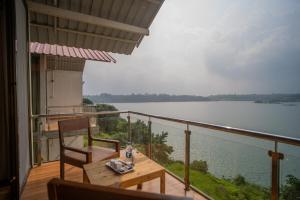 a balcony with a table and a view of a lake at Shvas Island Resort in Igatpuri