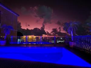 a swimming pool at night with a sunset in the background at Hotel Casa do Amarelindo in Salvador