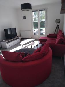 a living room with two red couches and a tv at La Villa Sokriss in Lanvallay