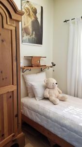 - un ours en peluche assis sur un lit dans une chambre dans l'établissement Shawnigan Lake Bed and Breakfast, à Shawnigan Lake